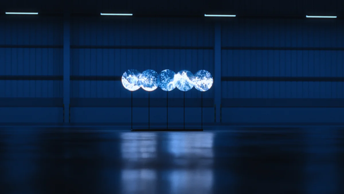 Cinq hélices holographiques alignées dans un hall industriel sombre, formant une image lumineuse bleue au-dessus du sol.